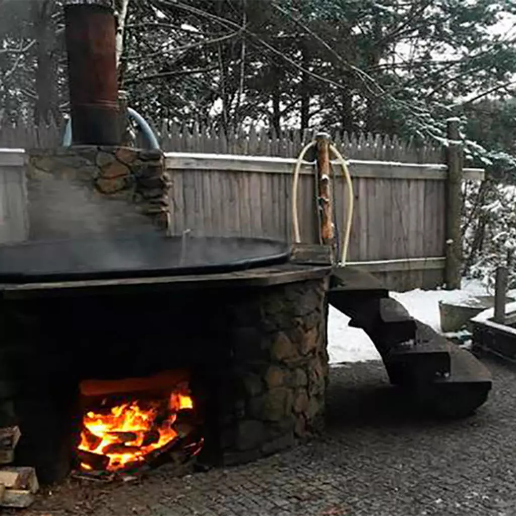 outdoor jacuzzi tub with fire in winter garden