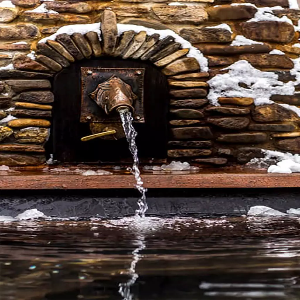 water flows from a decorative tap to hotpool